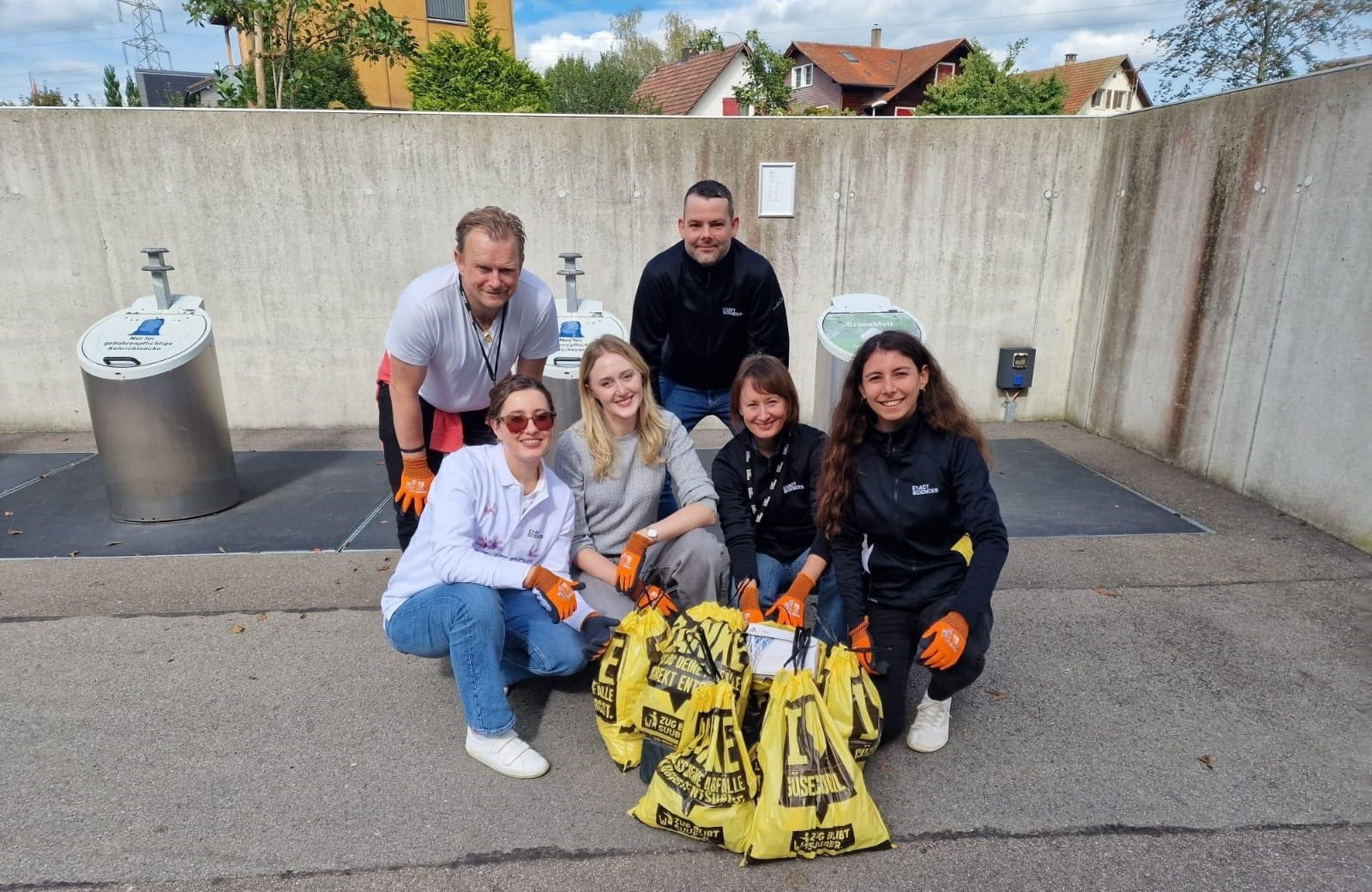 A group of volunteers smiling and proudly posing with filled trash bags.